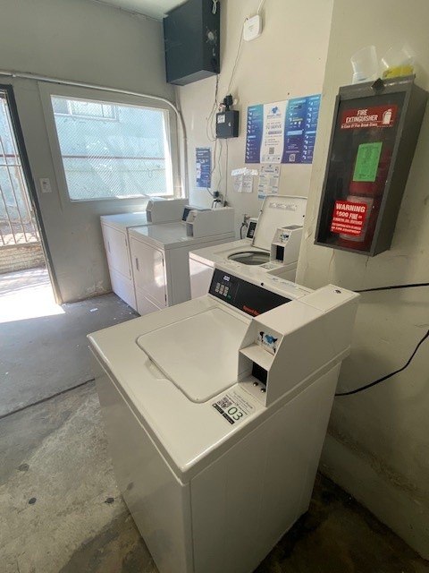 A white washing machine in a room with a warning sign on the wall.